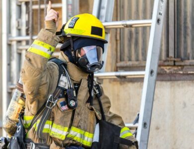 fireman wearing mask standing and about to climb on ladder