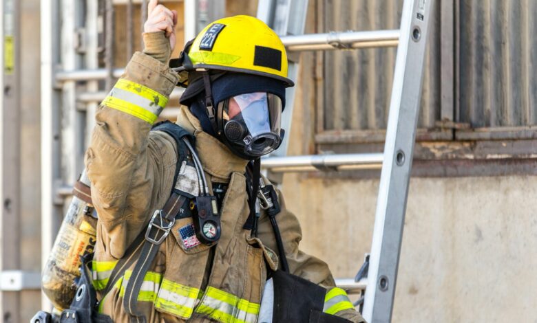 fireman wearing mask standing and about to climb on ladder